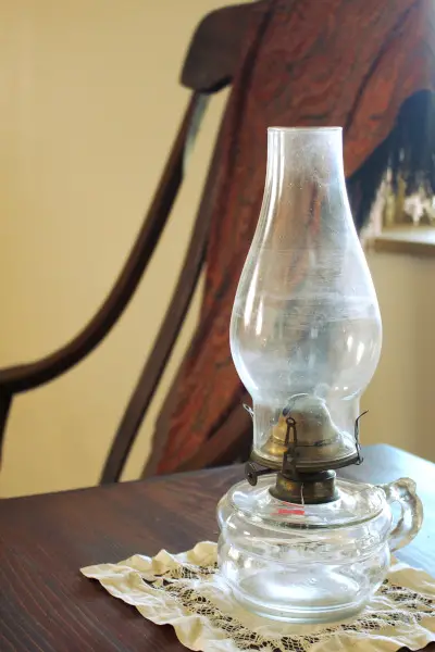Getting rid of clutter by keepin decor simple. An antique oil lamp sits on a table with a rocking chair next to it.