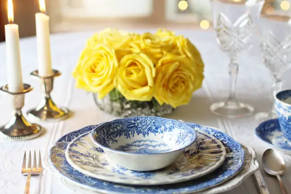 Curating a beautiful table setting with chinaware, candles, and flowers.