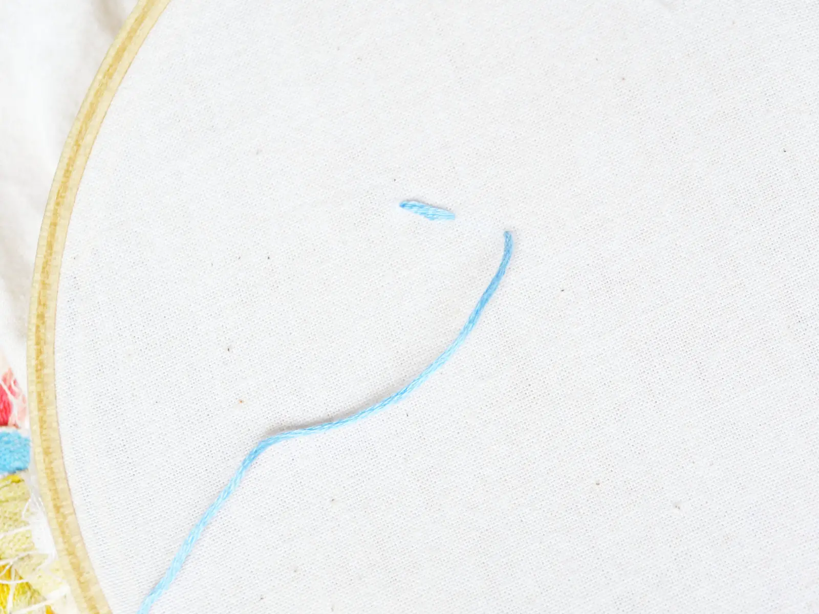 one completed running stitch in light blue floss