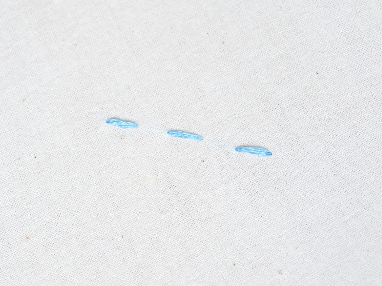 three running stitches in light blue floss