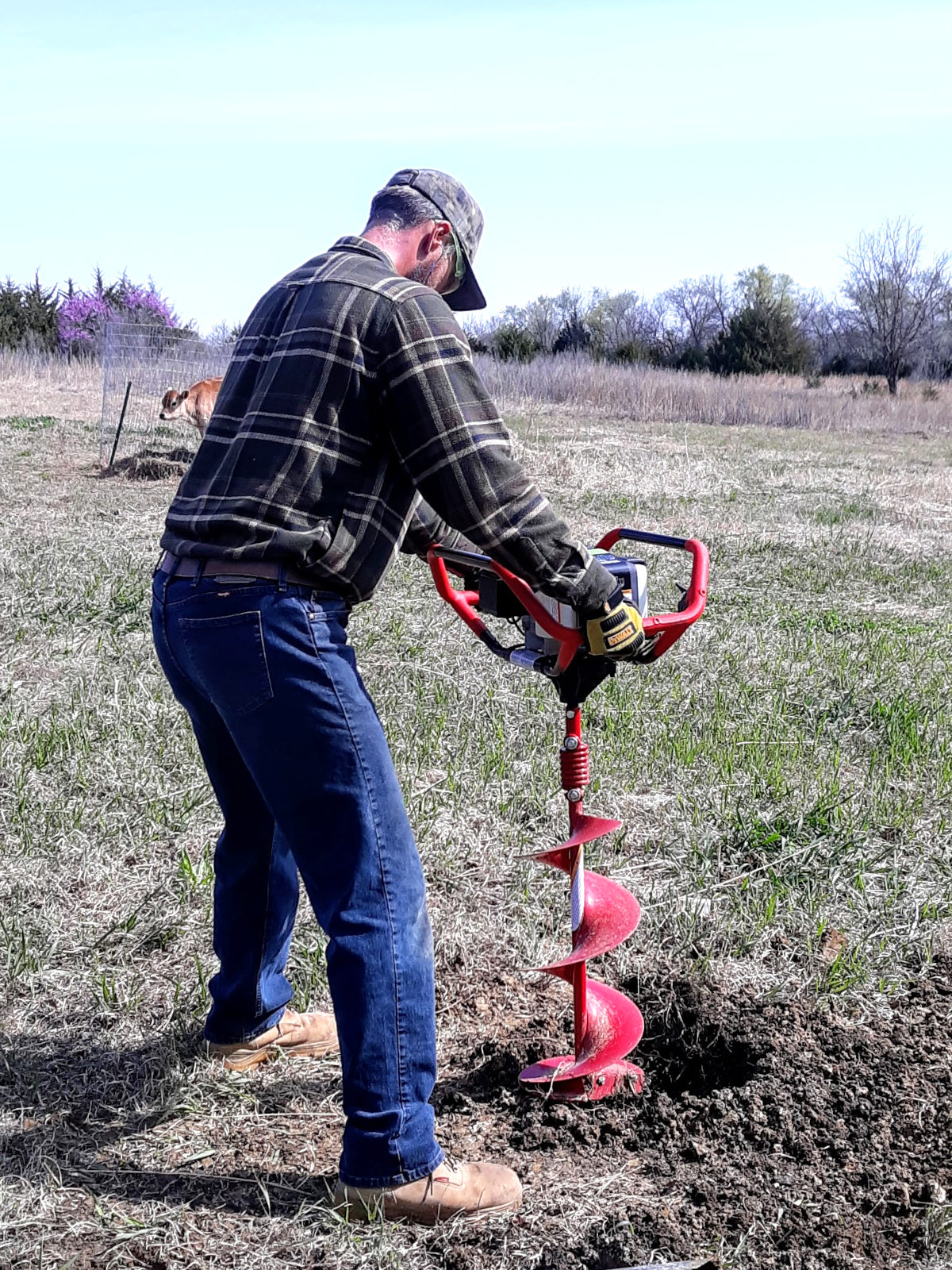 using auger to dig post hole for horse fence