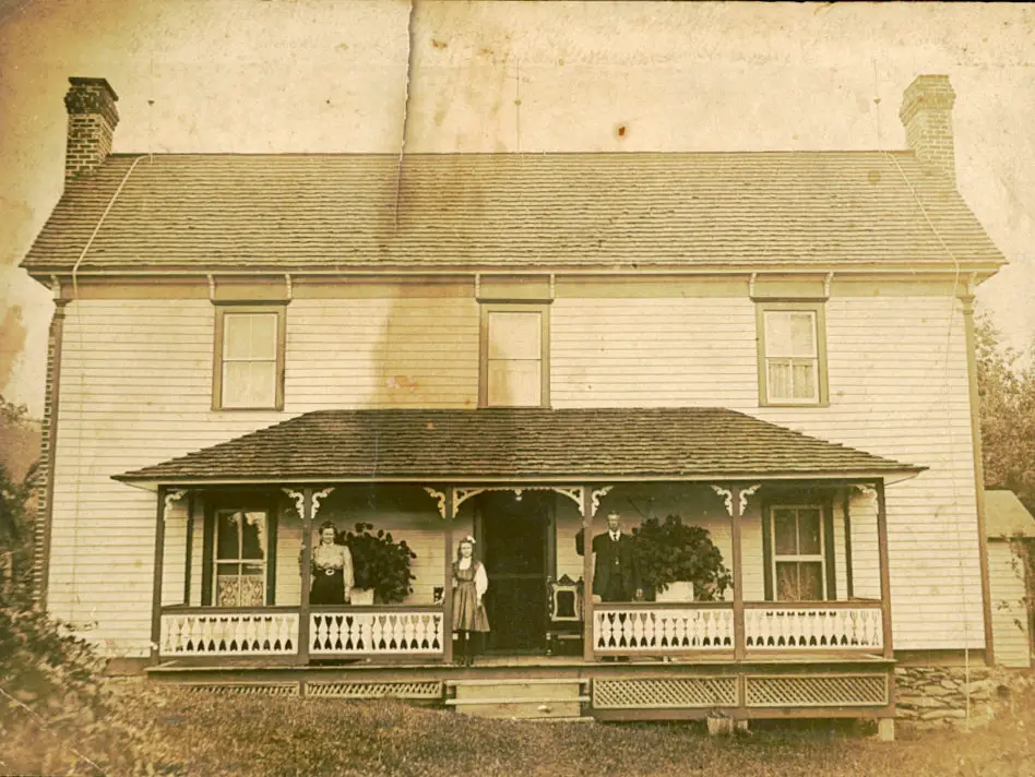 old farmhouse with people standing on front porch