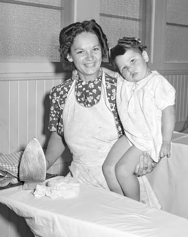 1940s housewife ironing and holding child