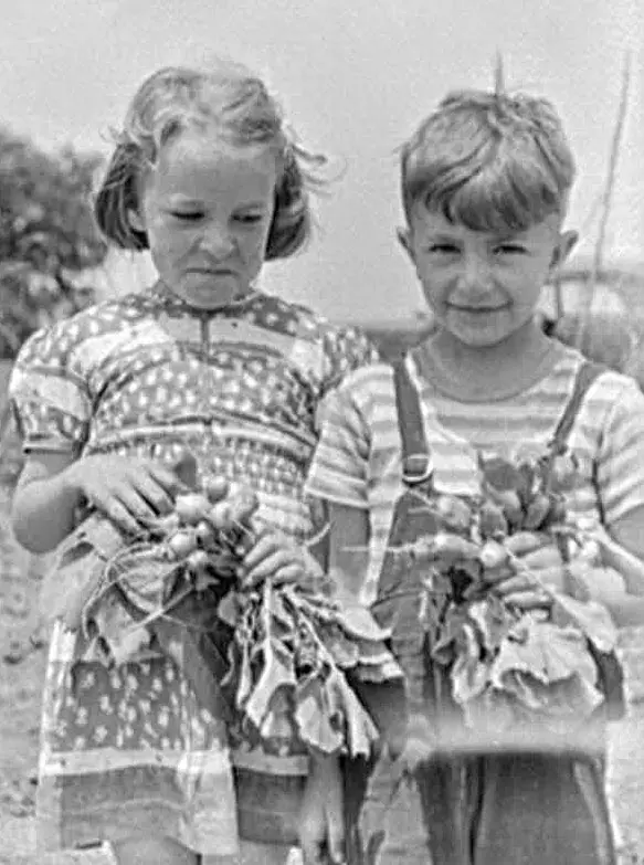 boy and girl holding produce from victory garden