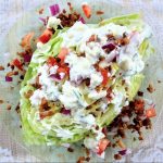 wedge salad on glass plate with dressing, bacon, tomato, and onion