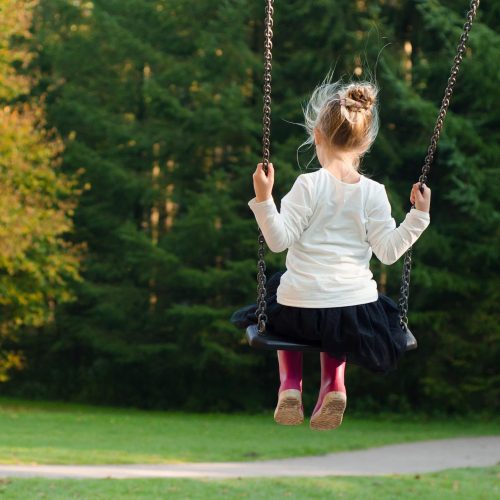 child swinging on wooden tree swing