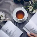 two poetry books, a cup of tea, and flowers on a table
